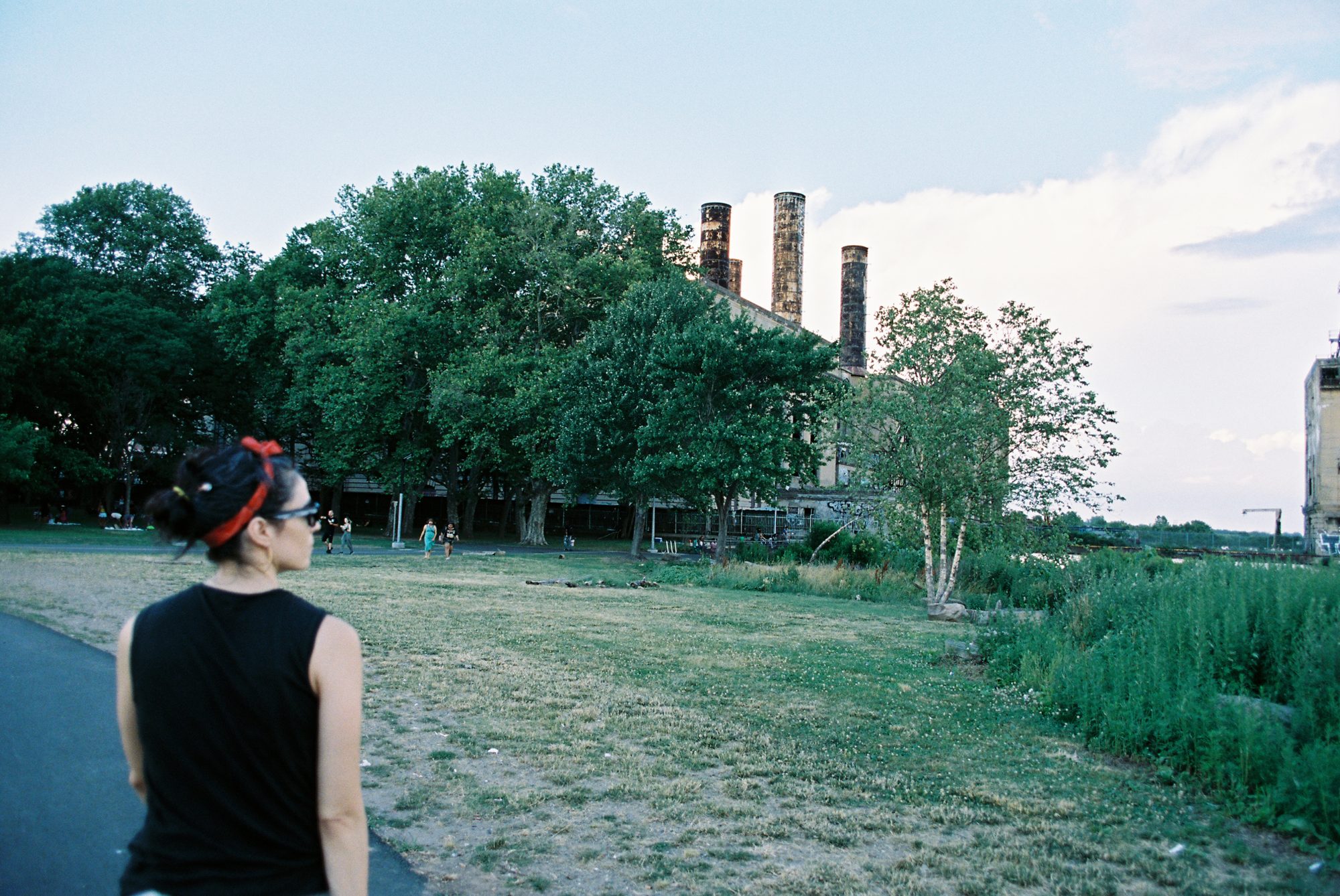 A woman looking toward old factory smokestacks