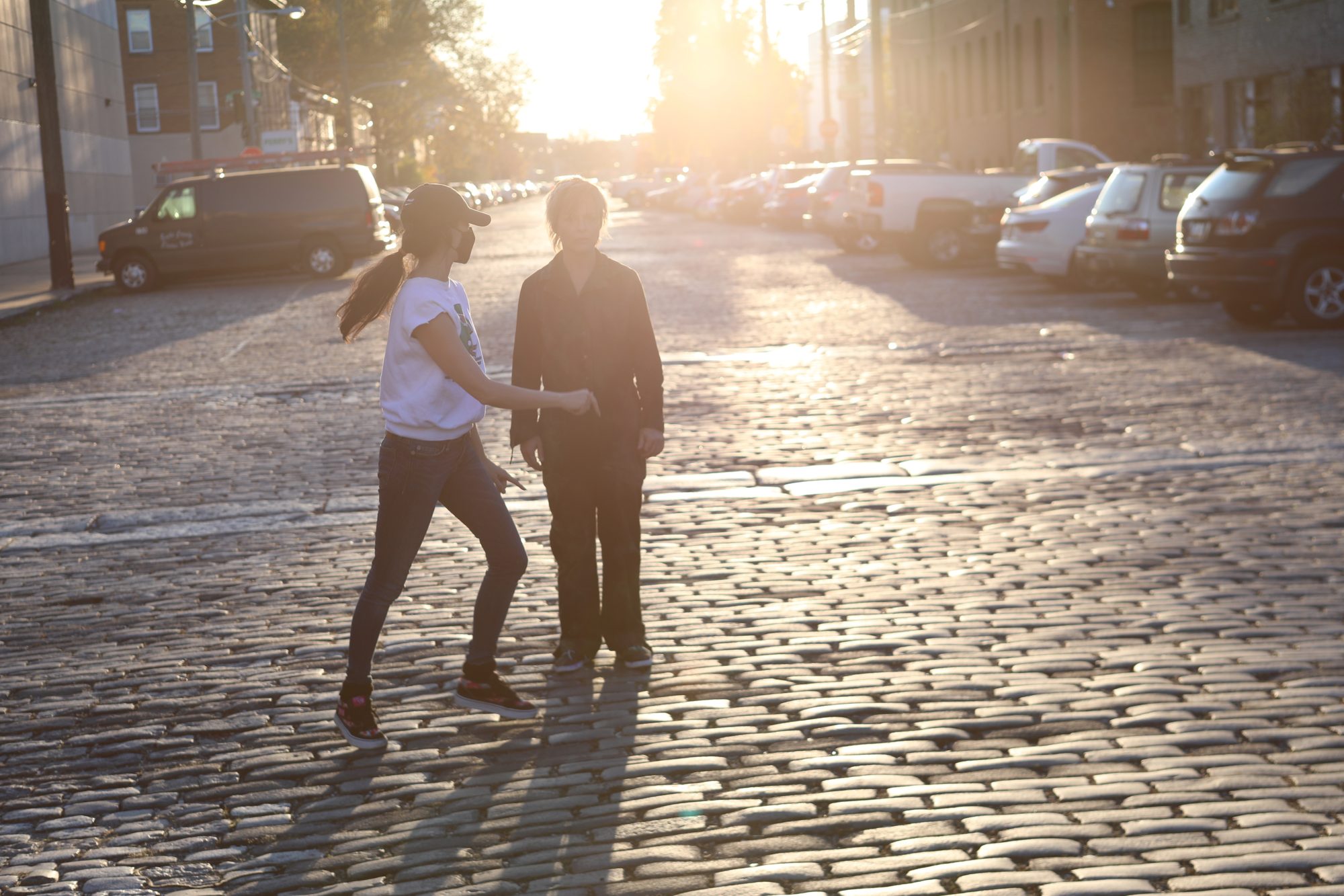 Two figures on a sunlit cobblestone street in Philadelphia